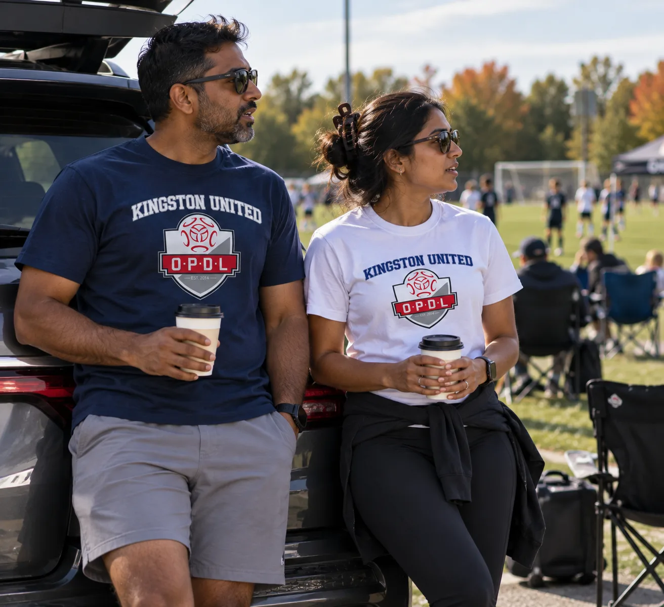 Parents wearing navy and white Kingston United OPDL Heavyweight Tees at the field